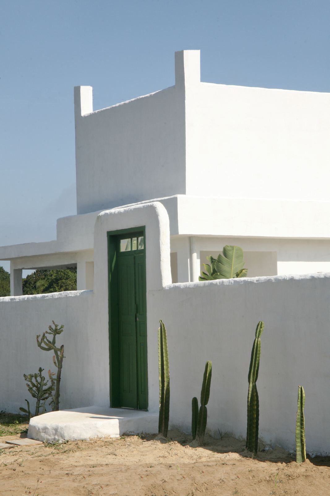 Fachada branca com porta verde da Casa ILHAMAR